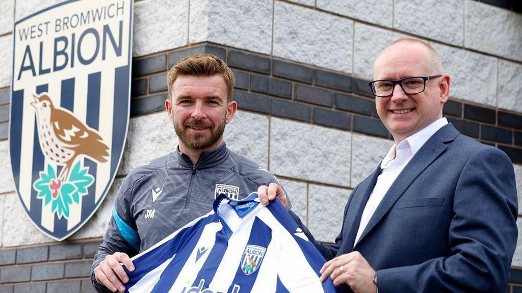 James Morrison is on the left and is holding a West Bromwich Albion home shirt with the club's executive director Mark Miles on the right.