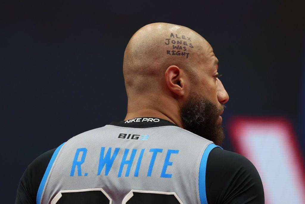 White in a basketball uniform with "Alex jones was right" written on his scalp in black marker