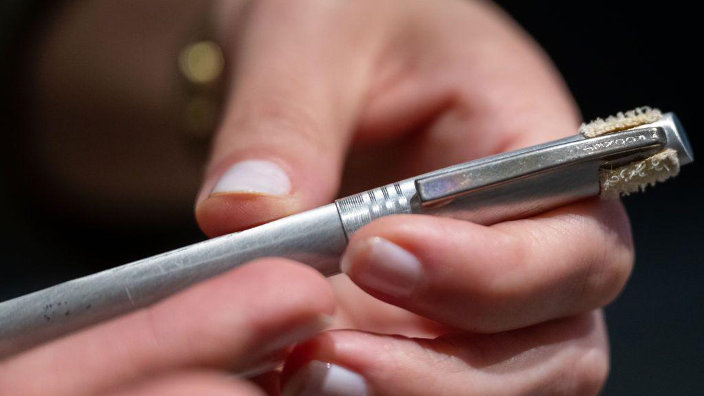A silver pen held in someones hands