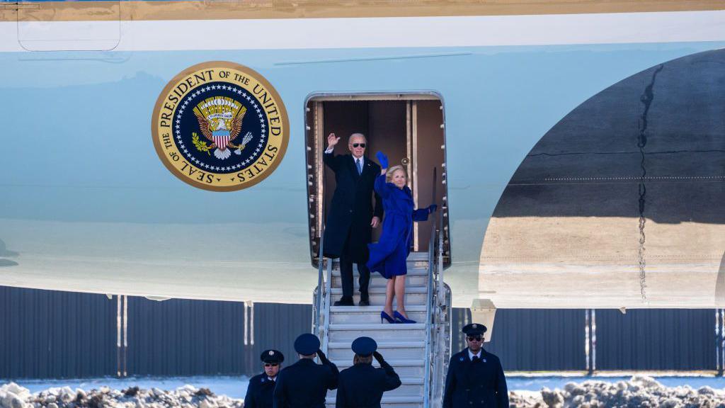 Former US President Joe Biden and former First Lady Jill Biden wave as they depart Joint Base Andrews on the steps of a plane.