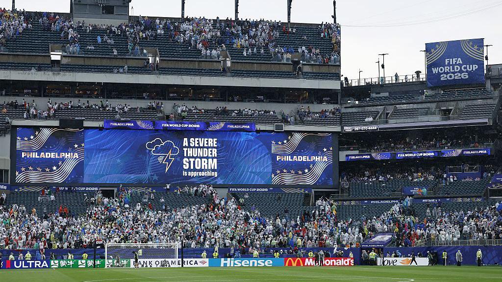 photo of part of a football pitch and side of a stadium with a big screen saying 'a severe thunderstorm is approaching'.
