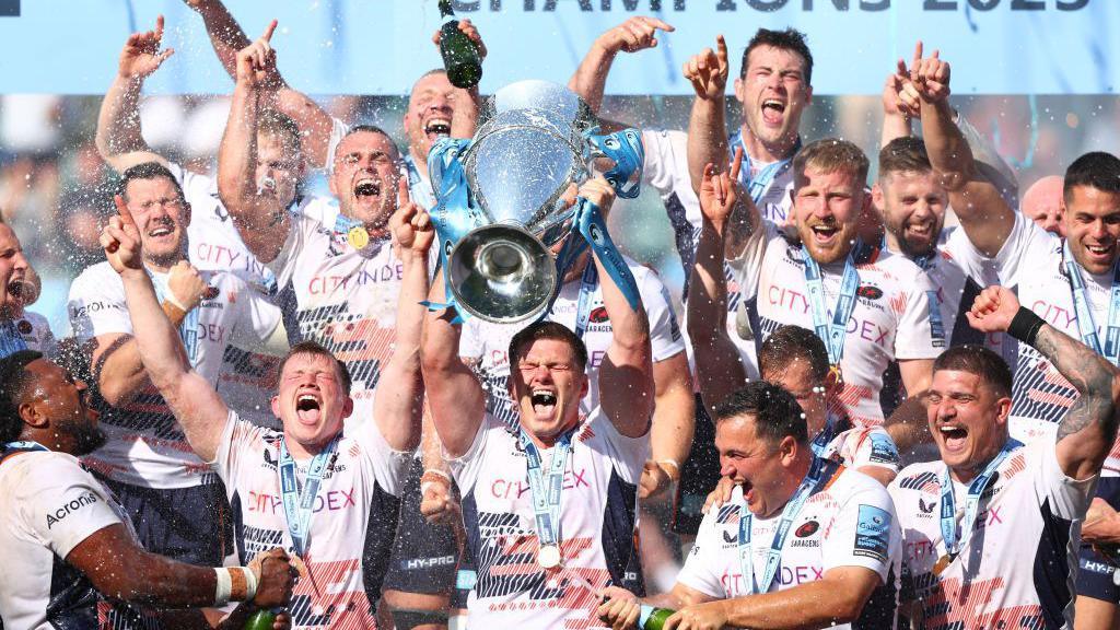 Owen Farrell holds the Premiership trophy aloft as Saracens players celebrate winning the 2022-23 league title
