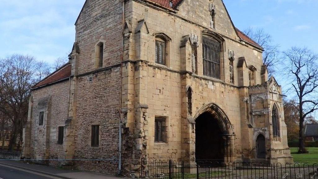 An old medieval brick gatehouse building with a large archway in the front.