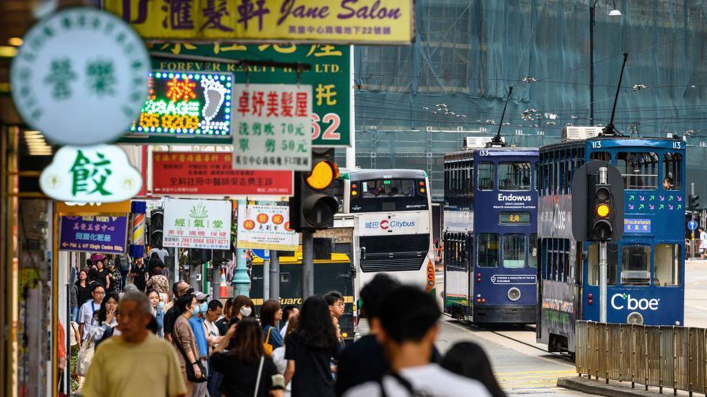 A view of a tram rumbling down the main street of the North Point district in Hong Kong on November 9, 2024. The pavement is crowded with people. 