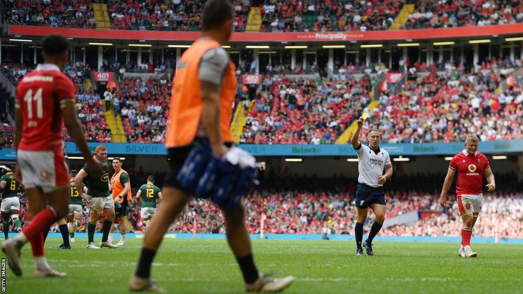 Referee Andrew Brace gives Rio Dyer of Wales a yellow card