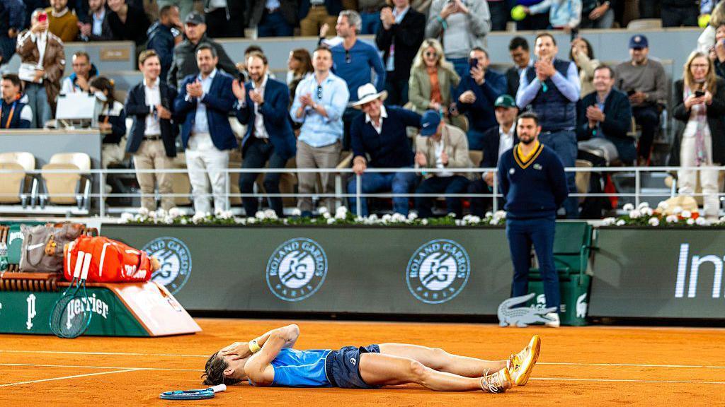 Lois Boisson lies on the floor with her hands on her face