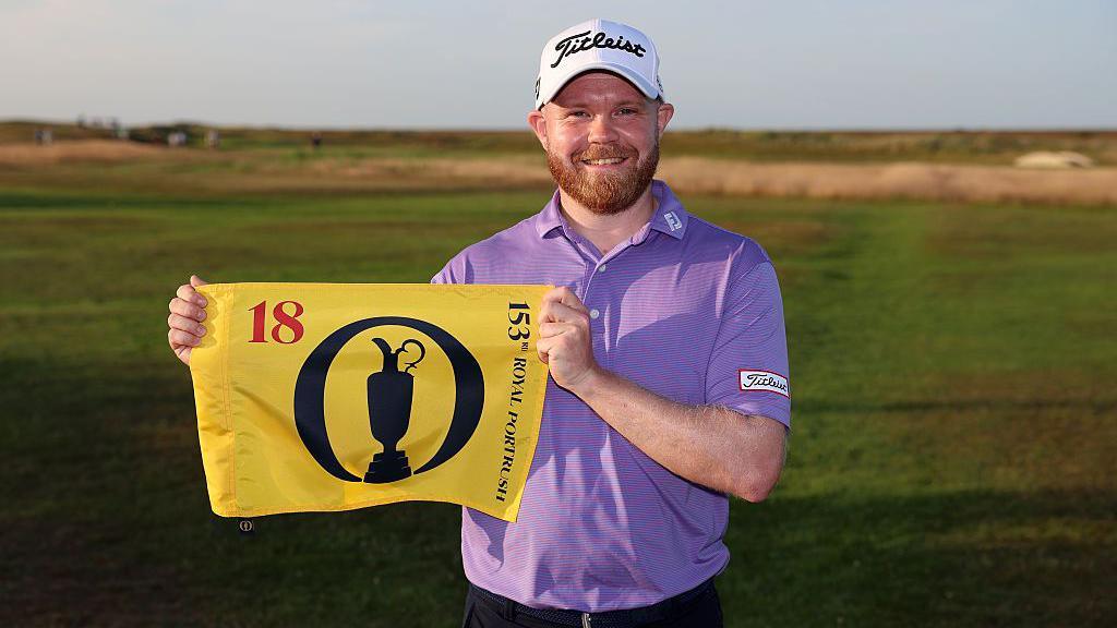 Nathan Kimsey poses with a pin flag after qualifying for the Open during final qualifying