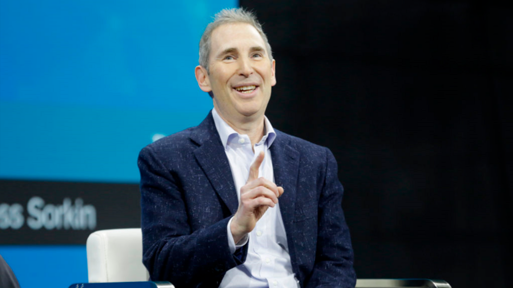 Amazon chief executive Andy Jassy sitting down, mid-sentence, gesturing with his hand. He is wearing a dark blue jacket with lighter flecks and a light blue shirt.