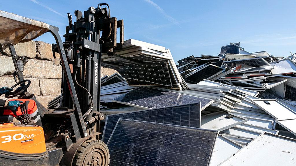 A fork-lift drops solar panels in a heap