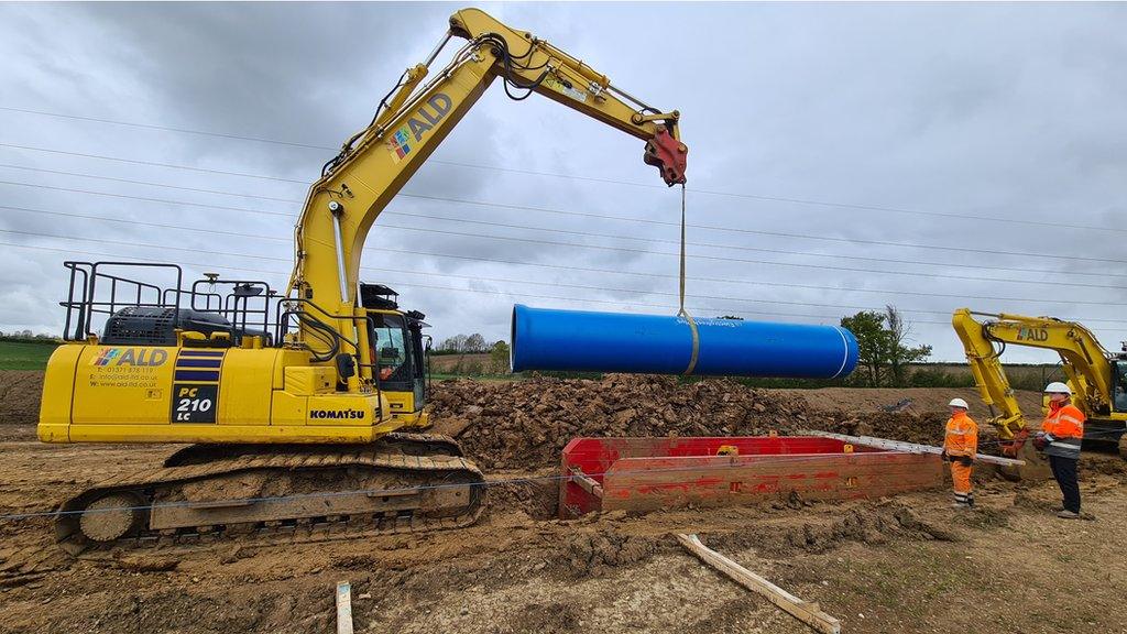 A water pipe being lowered into the ground by a digger near Abberton reservoir