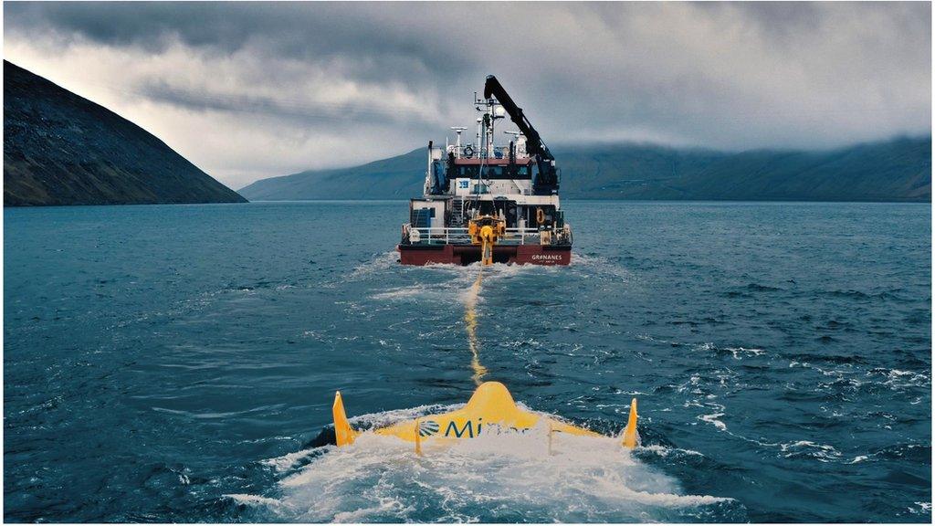 Ship pulling yellow floating machine behind it