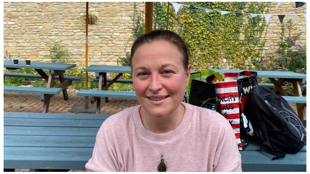 Woman in pink tee shirt outside community larder