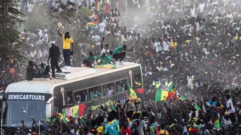 Aliou Cisse holds up the Africa Cup of Nations trophy in front of adoring fans