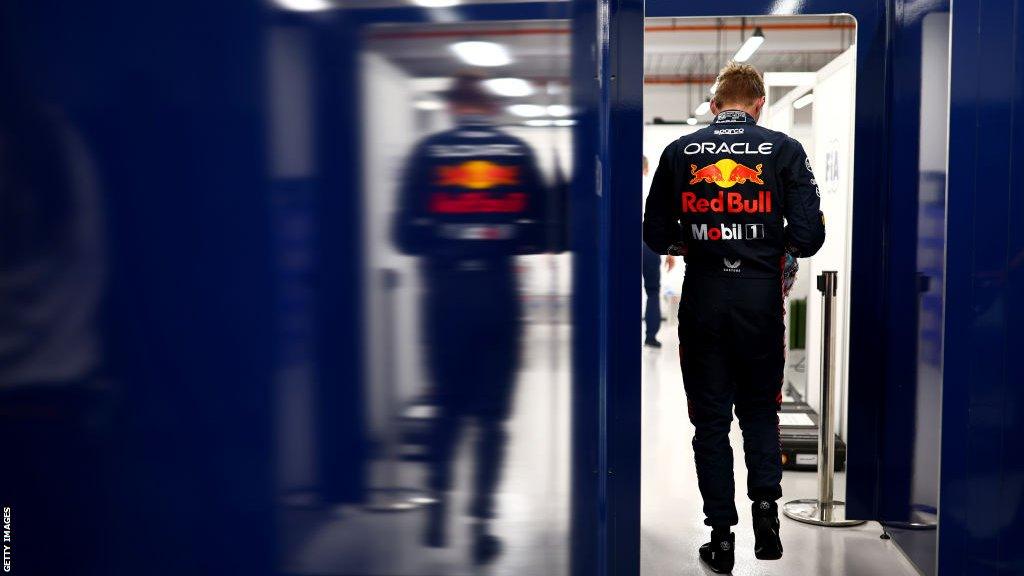 Rear view of Max Verstappen in the Red Bull garage with his reflection showing in the high-gloss wall