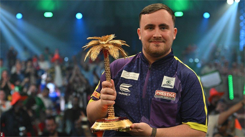 Luke Littler holds the Bahrain Masters trophy shaped like a palm tree