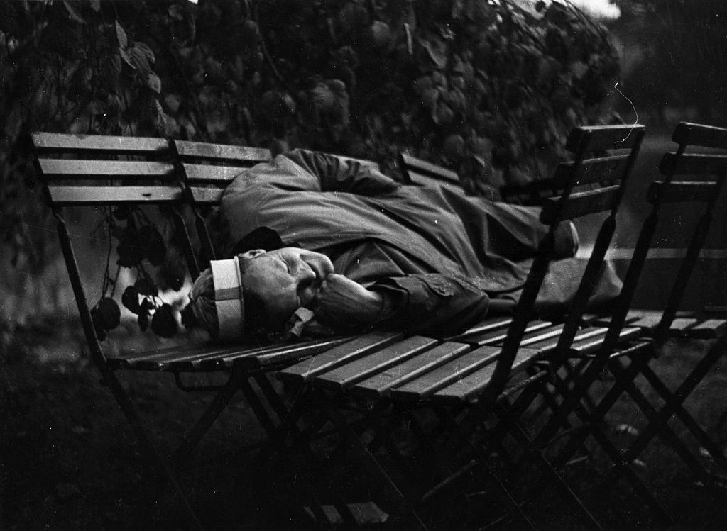 A man sleeps on chairs wearing a party hat