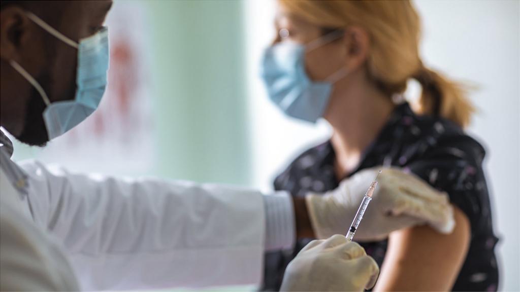 Doctor administering injection to young woman