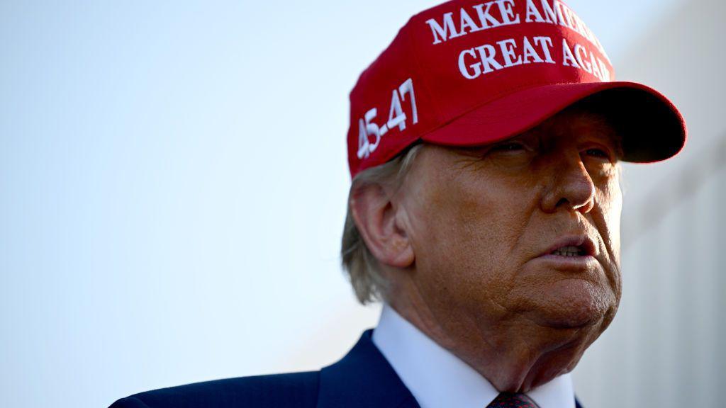 Close up of Donald Trump wearing a red baseball cap with his slogan Make America Great Again on the front and 45-47 on the side