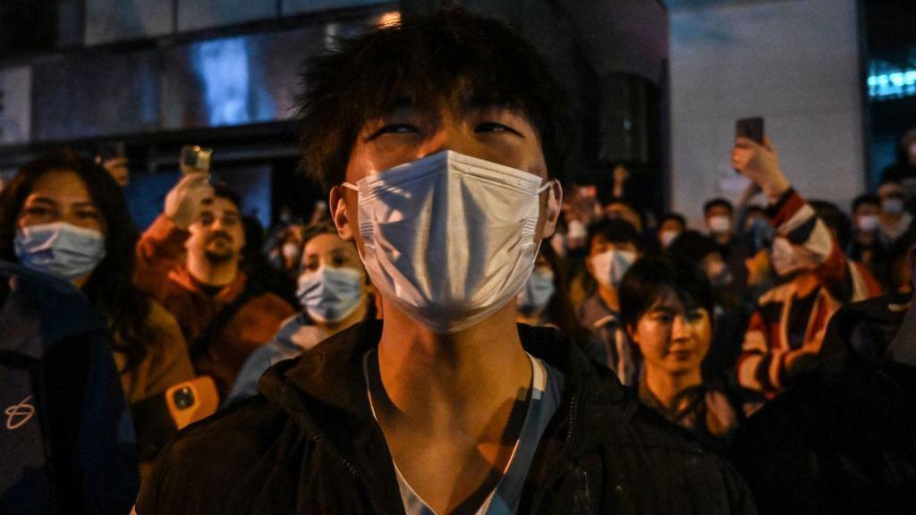 A young man in a mask at a protest along with several others against China's zero-Covid policy in Shanghai on November 27, 2022