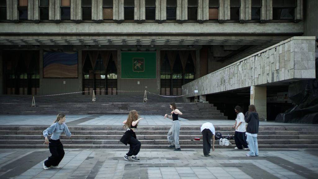 Teenagers dance on TikTok near Kharkiv's main theatre on 26 May 2024