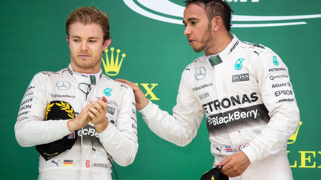 Lewis Hamilton and Nico Rosberg on the podium after the 2015 United States Grand Prix. Hamilton has placed his hand on Rosberg's shoulder but Rosberg is looking away from him