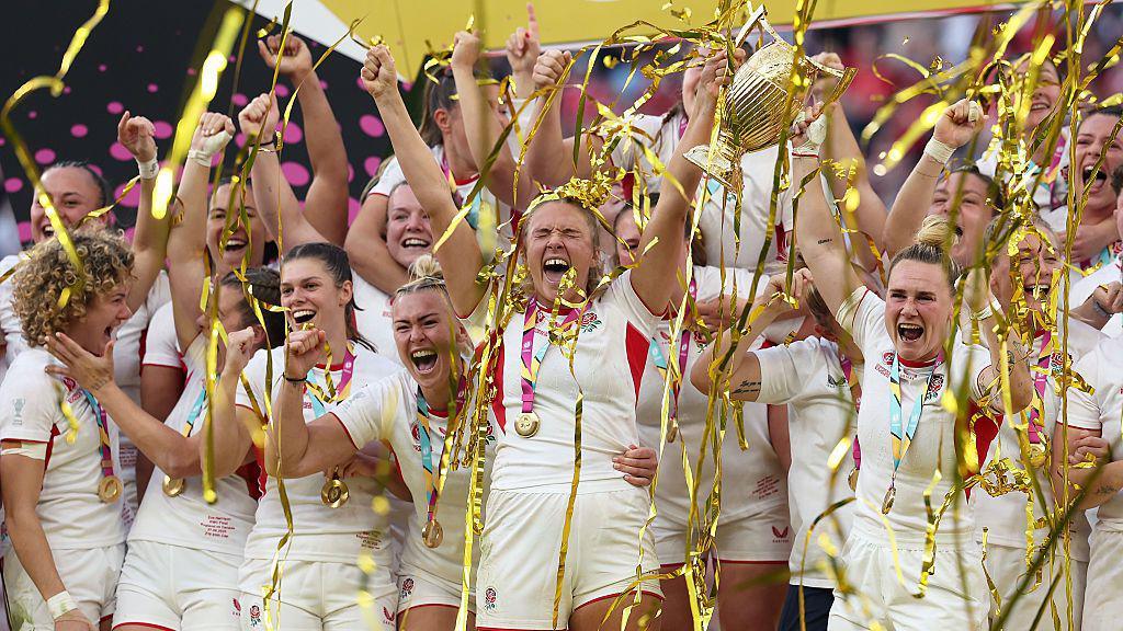 Zoe Aldcroft of England lifts the Women's Rugby World Cup trophy after defeating Canada