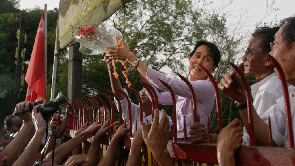 Myanmar's detained opposition leader Aung San Suu Kyi holds a bouquet of flowers as she appears at the gate of her house after her release in Yangon on November 13, 2010