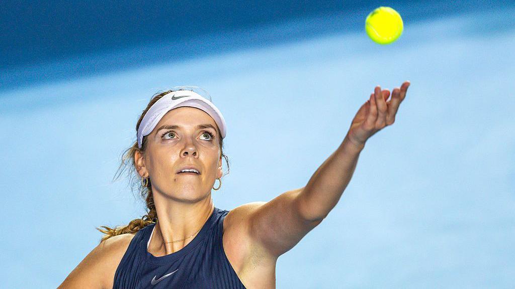 Katie Boulter tosses the ball in the air to serve