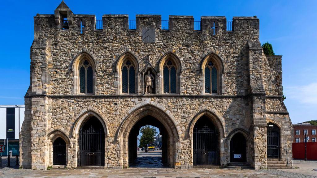 A two-storey medieval stone building with an archway going through the middle.