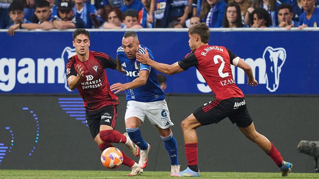 Santi Cazorla dribbles between two Mirandes players during the promotion play-off