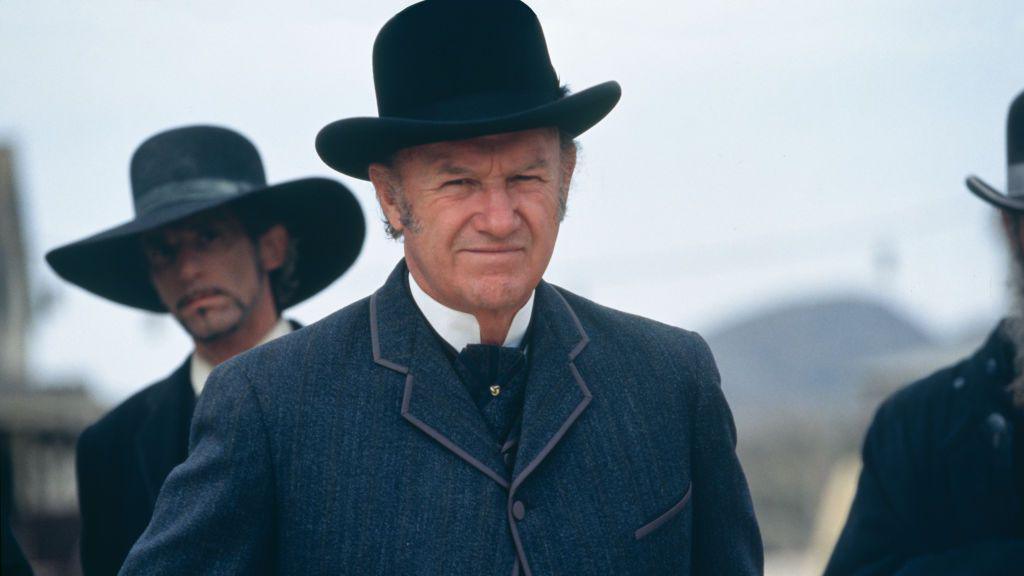 Gene Hackman in costume - an old-fashioned blue suit and bowler hat, sporting grey sideburns - on the set of Sam Raimi's 1995 movie "The Quick and the Dead". Two other actors are seen in similar dress in the background