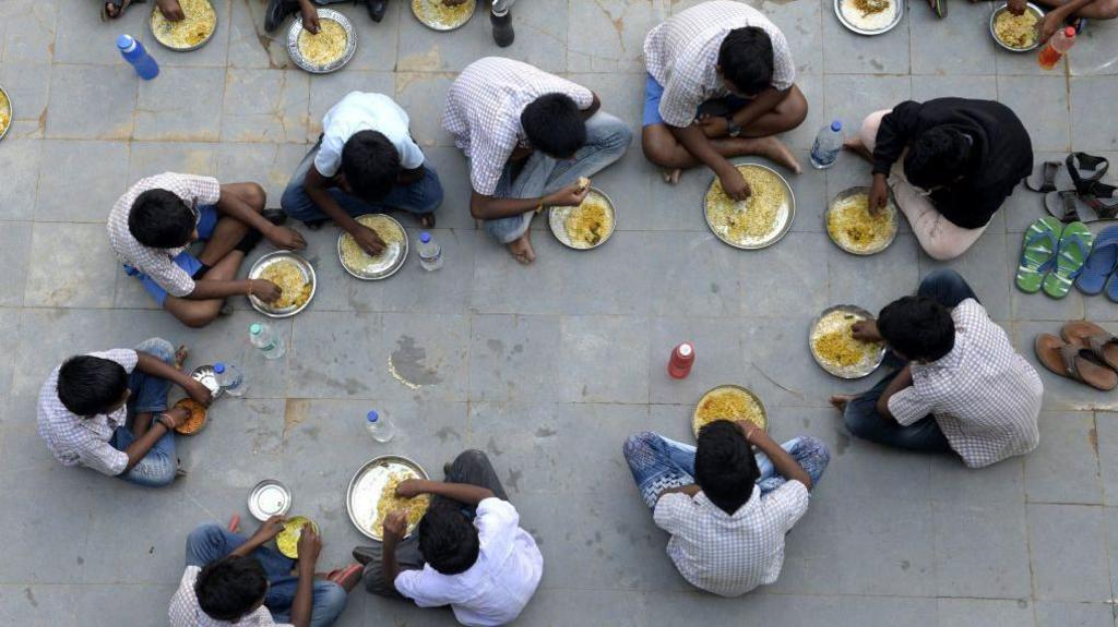Students eat their mid-day meal during lunch break at a government high school on the outskirts of Hyderabad on November 23, 2021