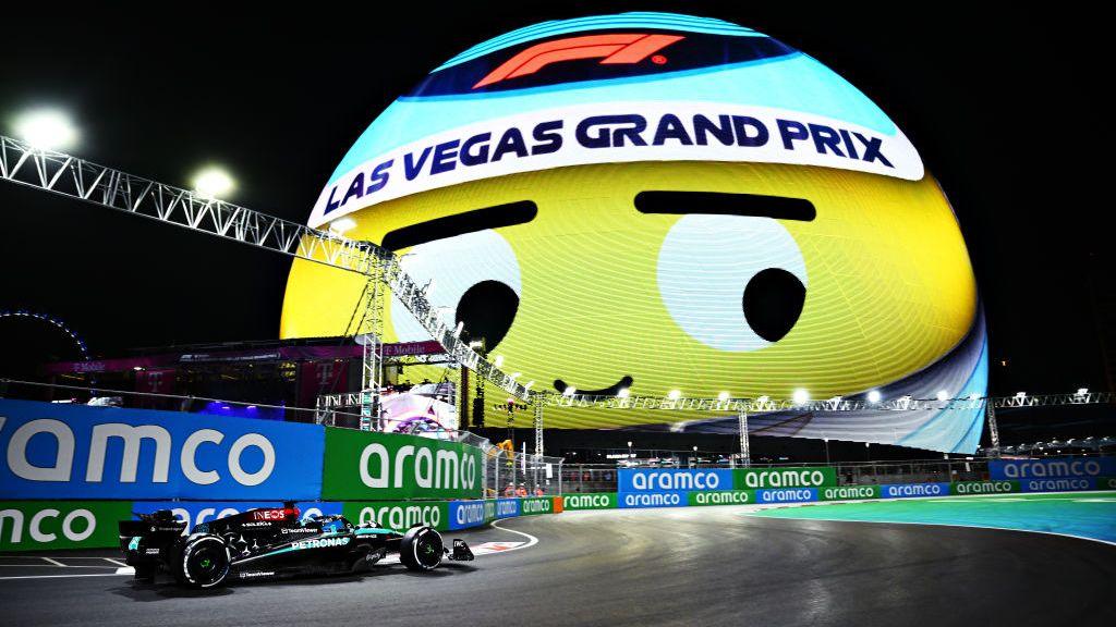 George Russell's Mercedes approaches the Sphere which displays a cartoon face with 'F1 Las Vegas Grand Prix' branding on top