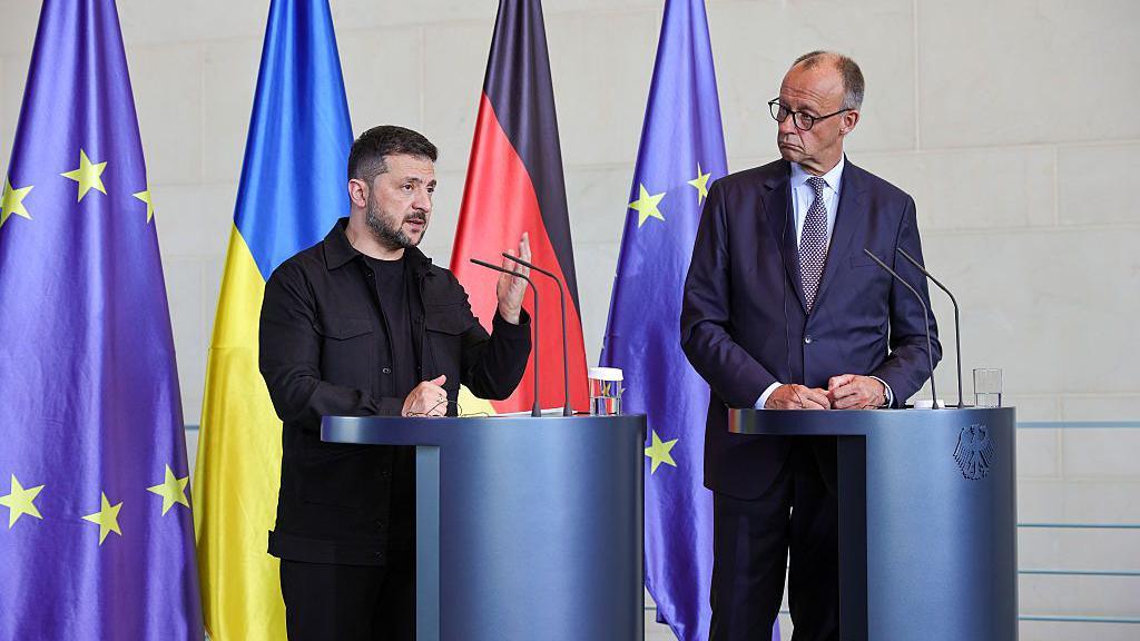 German Chancellor Friedrich Merz and Ukrainian President Volodymyr Zelensky stand next to each other at podiums as they attend a joint press conference at the Chancellery following a virtual meeting hosted by Merz between European leaders and US President Donald Trump