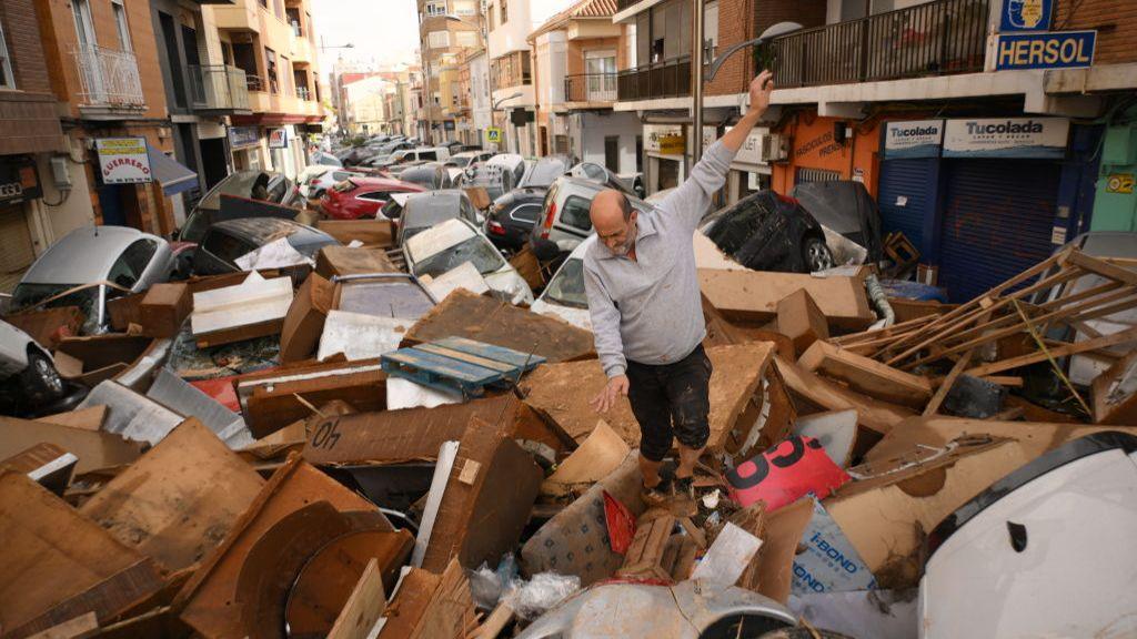 A man walks through a debris-covered street after flash floods hit the region on October 30, 2024 in the Sedaví area of Valencia