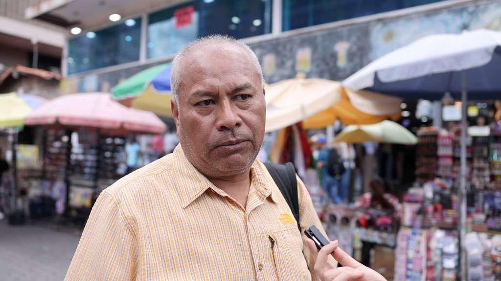 Javier Jaramillo looks towards the interviewer in front of some vendors' stalls in Caracas
