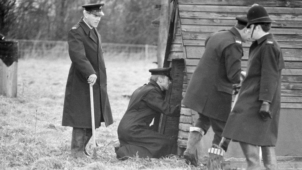 A black and white photo of police searching for the body of Muriel McKay in 1970