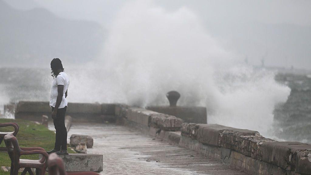 A man stands in front of a stormy sea