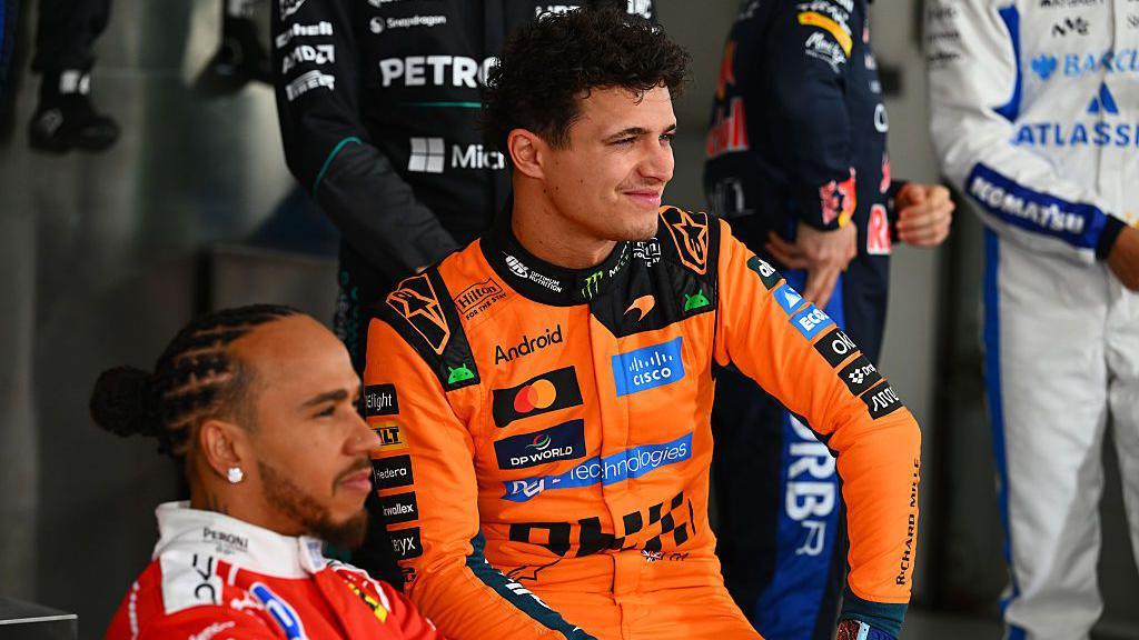 Lewis Hamilton, wearing his red Ferrari suit and Lando Norris, wearing his papaya Mclaren suit, pose during the F1 2026 photocall in Bahrain
