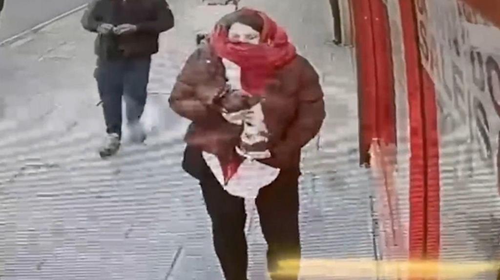 Constance Marten holding baby in east London with scarf covering face