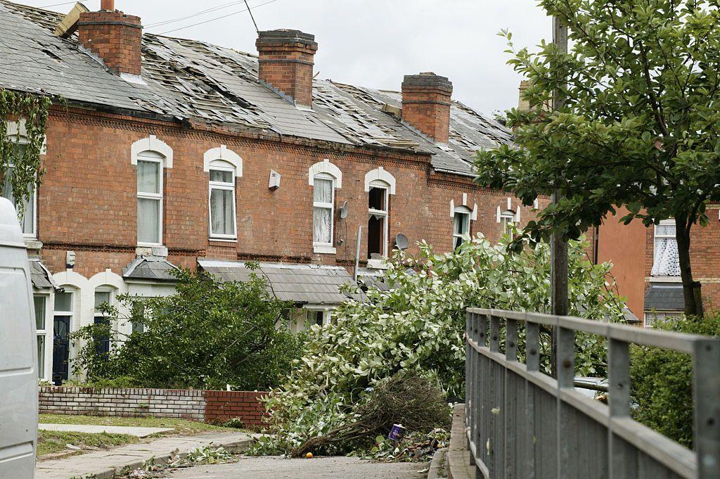 Line of houses showing roof damage and fallen tree