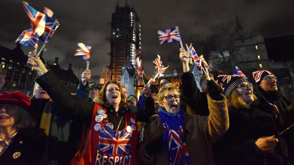 Brexit supporters waving Union Jacks outside Parliament celebrate the UK leaving the EU on 31 January 2020. 