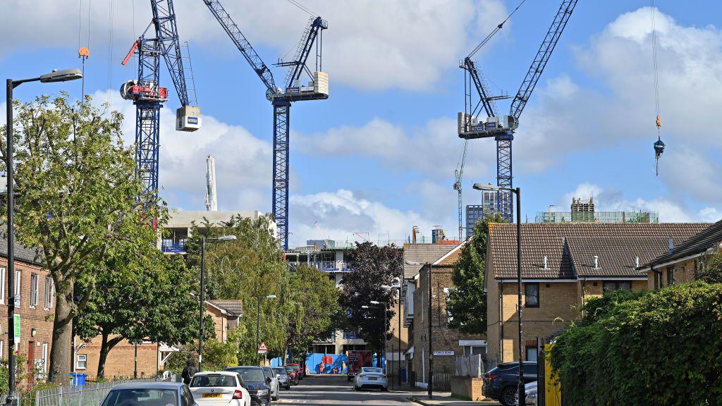 Cranes tower above a residential street in south of England on a sunny day.