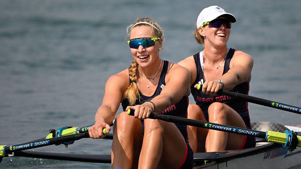 Becky Wilde smiling as she holds onto the oars while rowing at the Paris 2024 Olympic Games, Mathilda Hodgkins-Byrne is in the boat behind her, also holding oars