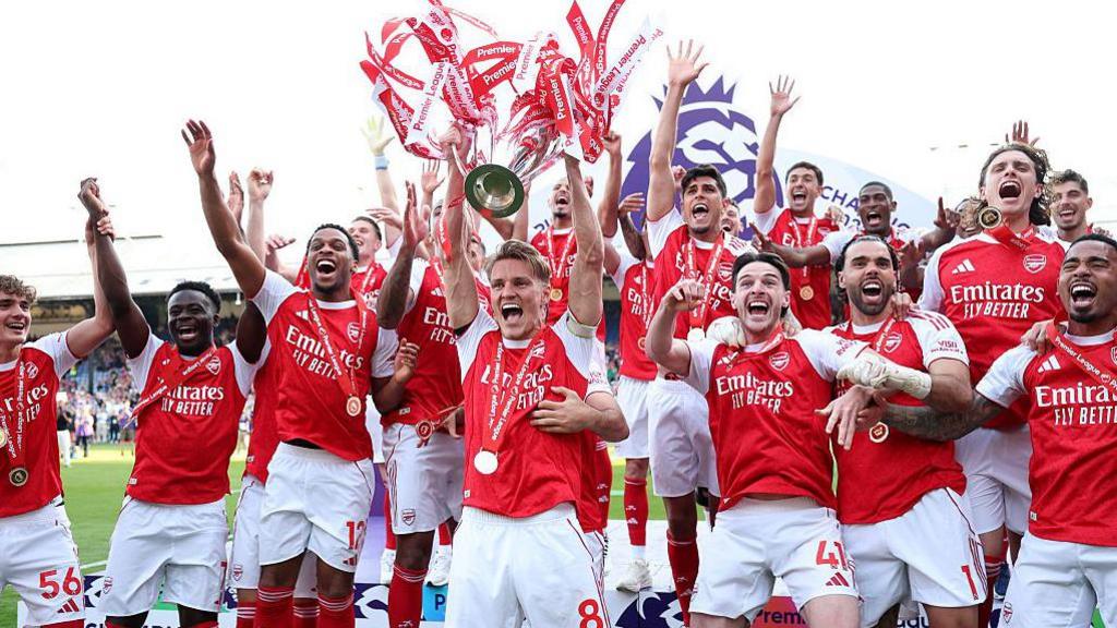 The Arsenal team lifts the Premier League trophy. 