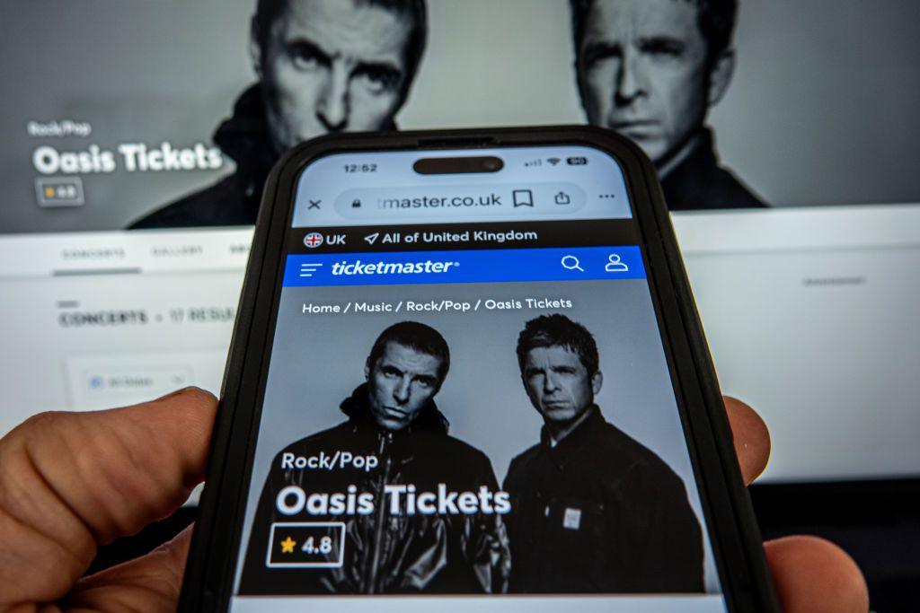 A laptop and a smart phone displays the Ticketmaster website with the Oasis gig details on.