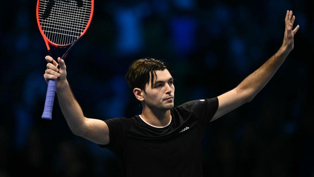 Taylor Fritz holds up both arms in celebration of his win