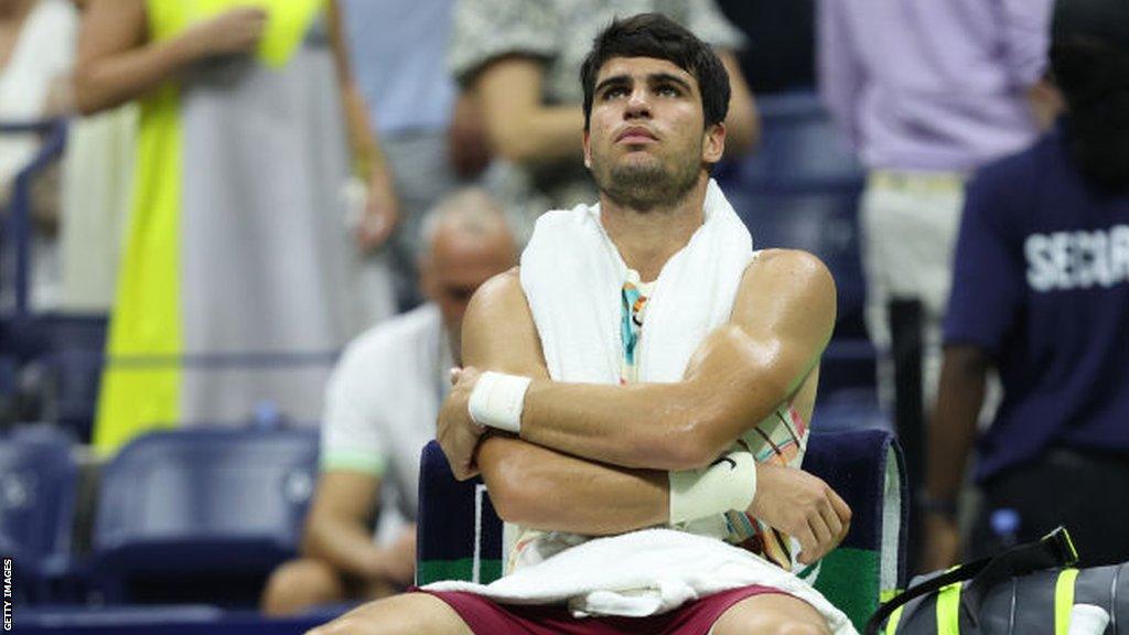 Carlos Alcaraz sits on his chair with his arms folded