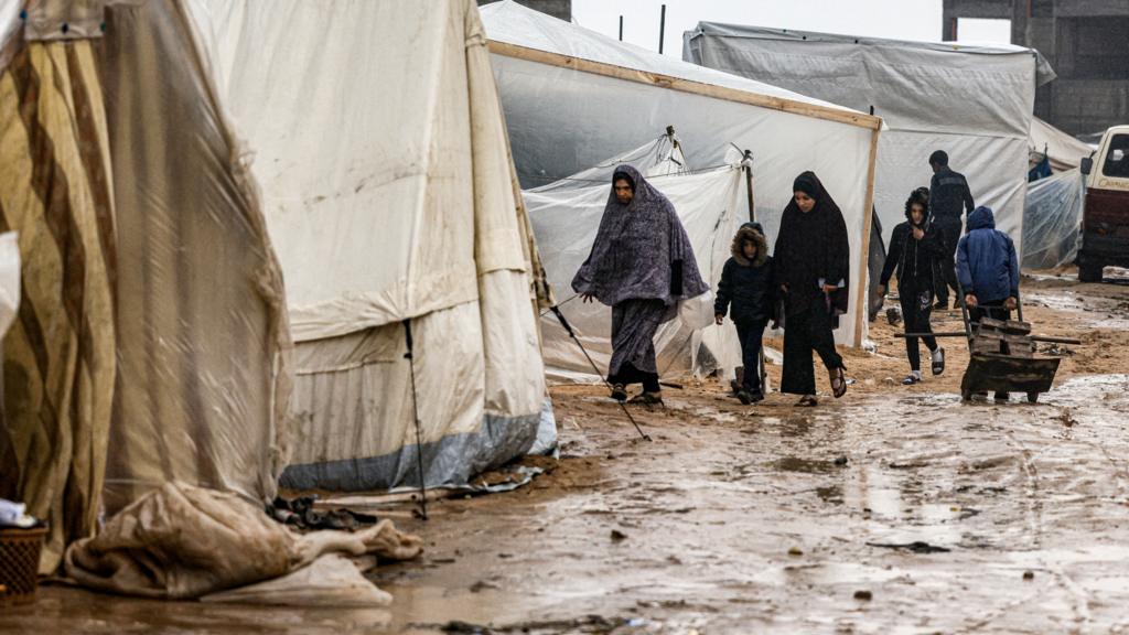 People walk in Rafah following heavy rain on 13 December