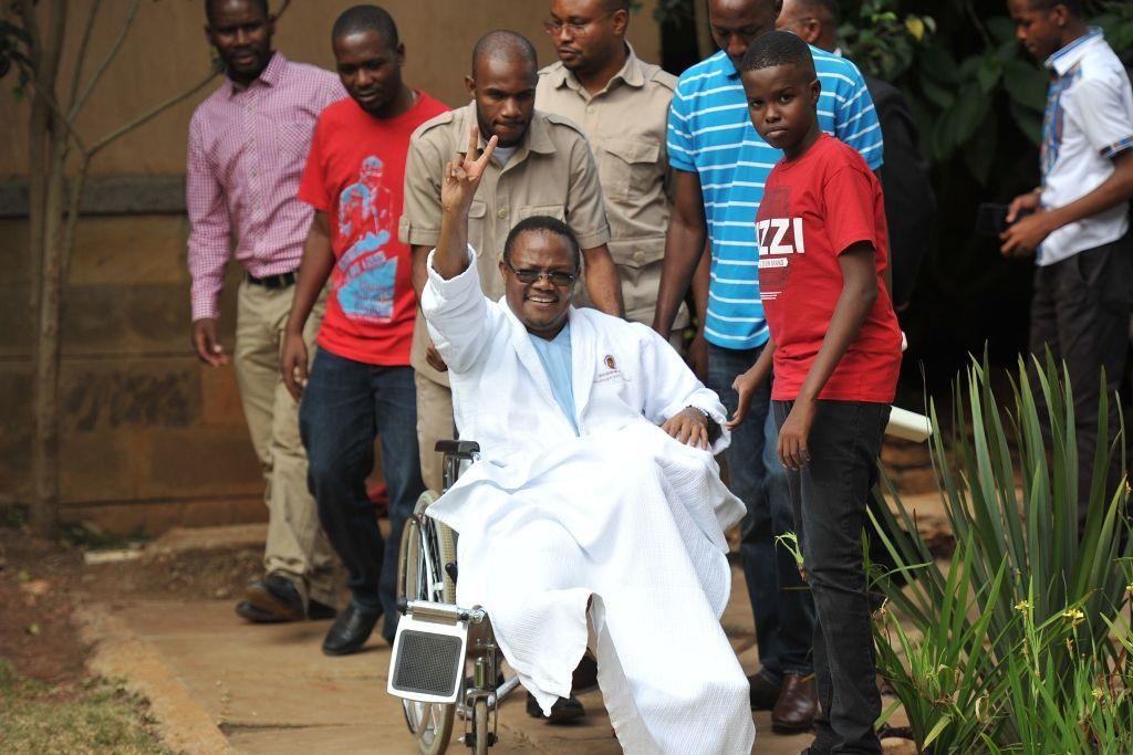 Tundu Lissu waves from his wheelchair after giving a press conference surrounded by members of his family and supporters on 5 January 2018 at a hospital in the Kenyan capital, Nairobi